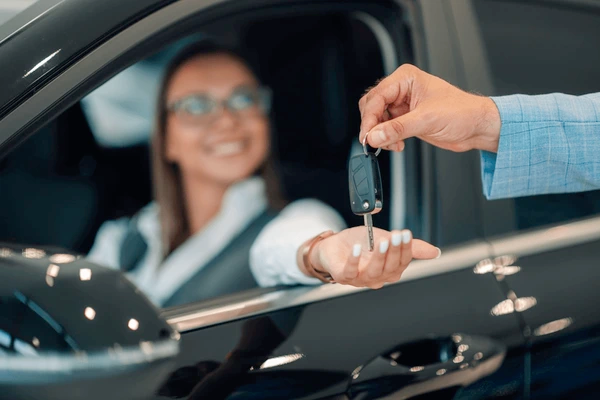 A professional hand holding a car key over a digital contract